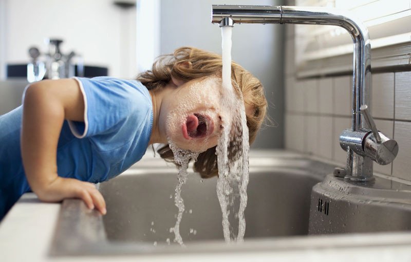 Child with face under faucet